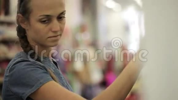 年轻漂亮的女人在超市里看化妆品视频的预览图