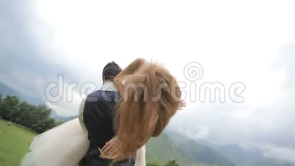 结婚纪念日幸福的新婚夫妇在群山的背景下玩得很开心视频的预览图