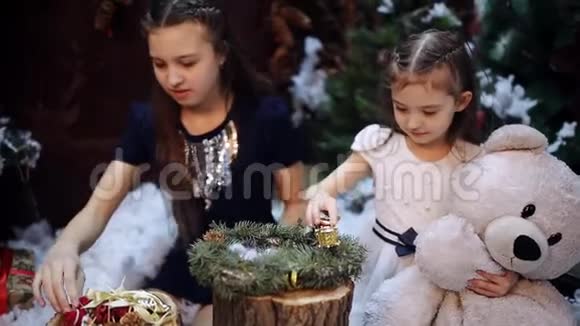 两个小妹妹在圣诞树上为祖母准备礼物快乐的女孩和家人两个小女孩在视频的预览图