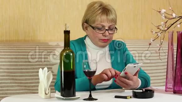 女人坐在桌子旁在智能手机上说话视频的预览图