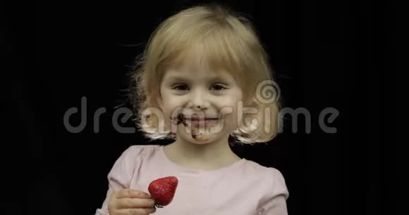 有着融化的巧克力和鲜奶油的脏脸的孩子吃草莓视频的预览图