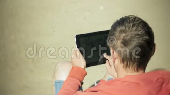 一个人坐在船边的沙滩上戴着耳机用平板电脑视频的预览图