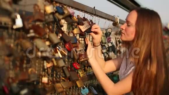 可爱的少女在情人桥上寻找挂锁看到锁旅行视频的预览图