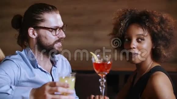 黑胡子的嬉皮士在豪华酒吧里和一个非常漂亮开朗的黑人花哨女人调情他们喝酒视频的预览图