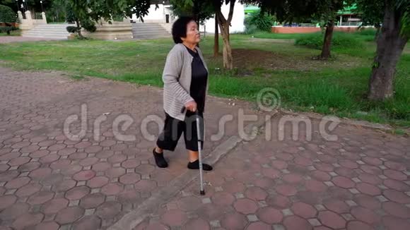 在公园里用手杖走路的老年妇女的慢动作视频的预览图