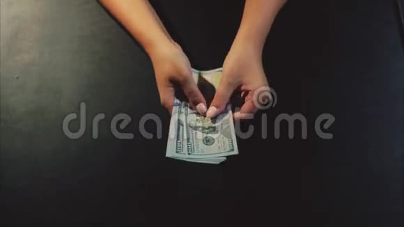 女人的手在黑色的背景上显示着美元钞票的粉丝视频的预览图