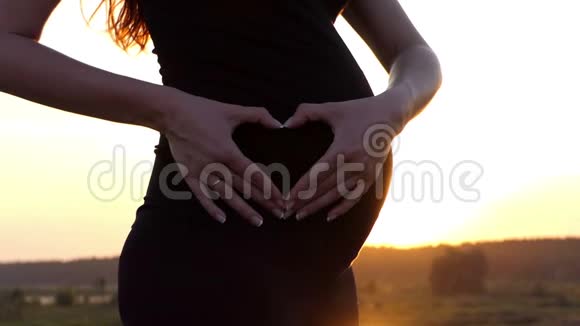 夕阳西下怀孕少女肚子上美丽的心视频的预览图