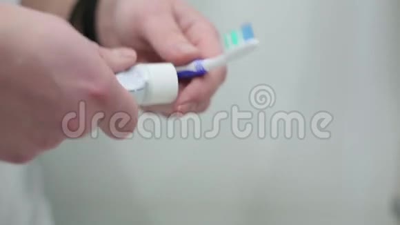 男人把牙膏放在牙刷特写上视频的预览图