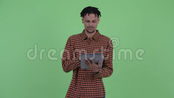 快乐年轻英俊的非洲男人用数码平板电脑思考视频的预览图