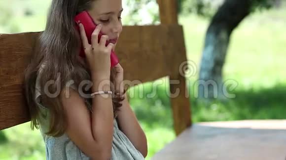 有智能手机的漂亮女孩坐在避暑别墅的长椅上视频的预览图