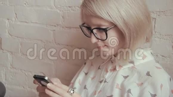 快乐的年轻美女在咖啡馆里喝着咖啡在智能手机上发短信视频的预览图