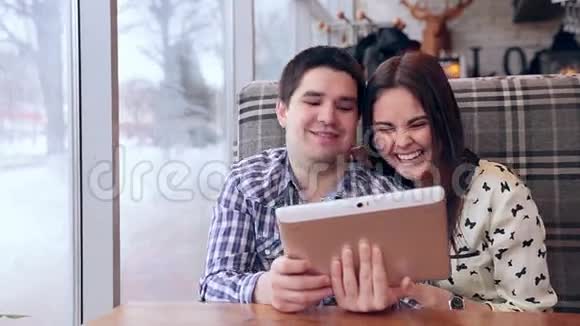 年轻夫妇在咖啡馆里使用数字平板电脑视频的预览图
