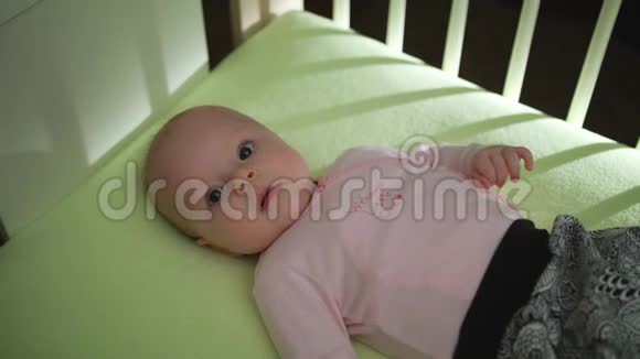 可爱的宝宝躺在床上双手双腿移动粉红色的布视频的预览图