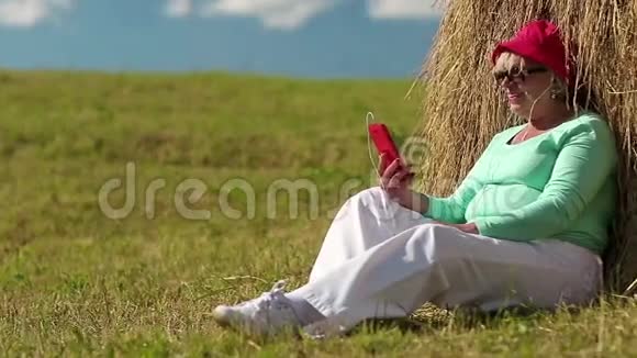女人坐在绿草上通过手机交流视频的预览图