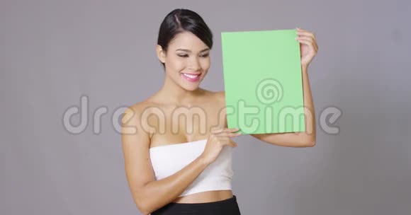 有魅力的女人拿着一个空白的绿色标志视频的预览图