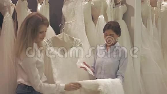 微笑美丽的新娘集团在婚礼时装店选择白色礼服视频的预览图