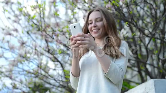 在智能手机上使用应用程序的女人微笑着在手机上发短信视频的预览图