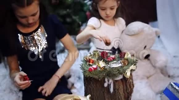 两个小女孩在圣诞树上为祖母准备礼物视频的预览图