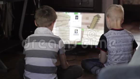 两个男孩坐在家里玩电脑游戏视频的预览图