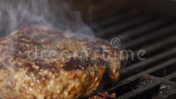 在靠近火焰和烟雾的烤架上缓慢移动牛肉汉堡视频的预览图