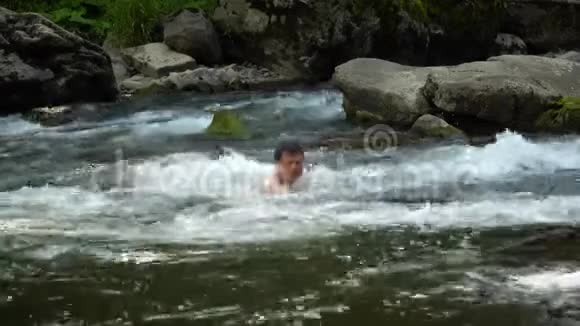 那家伙正在河里游泳一个年轻可爱的家伙在一条干净的山河里洗澡他很开心视频的预览图