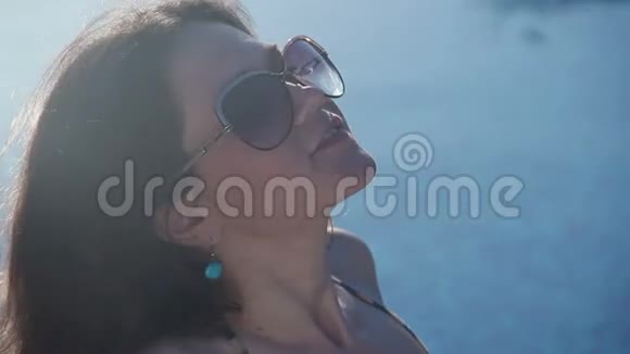 在度假胜地阳光下晒太阳的戴墨镜的女人视频的预览图