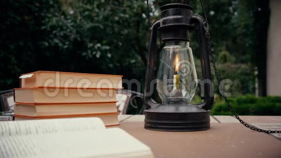 花园里桌子上有煤油灯和订书机手把书放在桌子上秋天视频的预览图