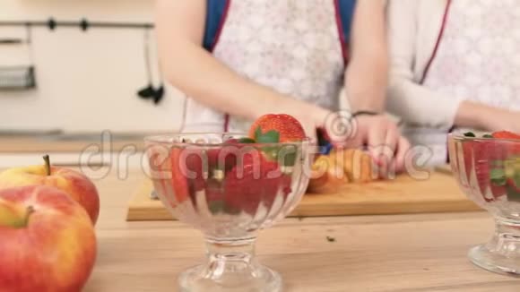 一个男人和女人用草莓准备水果沙拉的手的特写视频的预览图