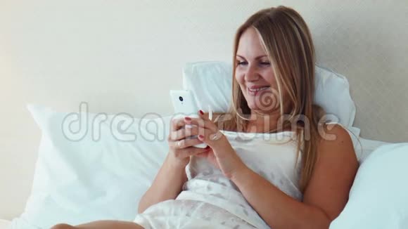 躺在床上用智能手机的金发美女视频的预览图