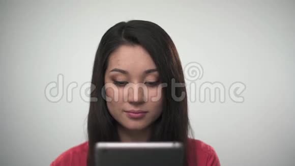 使用平板电脑和对着镜头微笑的漂亮亚洲女孩的肖像视频的预览图