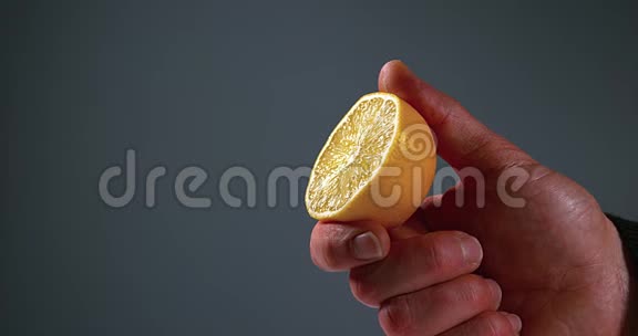 男人的手在黑色背景下挤压柠檬柑橘柠檬视频的预览图