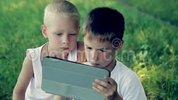 孩子们在公园里玩平板电脑视频的预览图