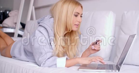 幸福的女人躺在沙发上拿着自动取款机视频的预览图