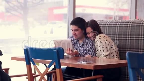 年轻夫妇在咖啡馆里使用数字平板电脑视频的预览图