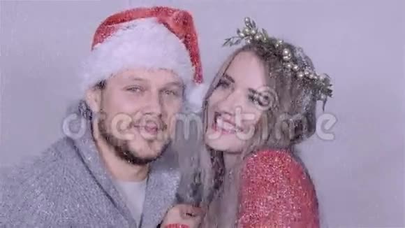 年轻的圣诞夫妇在白色的背景下享受白雪视频的预览图