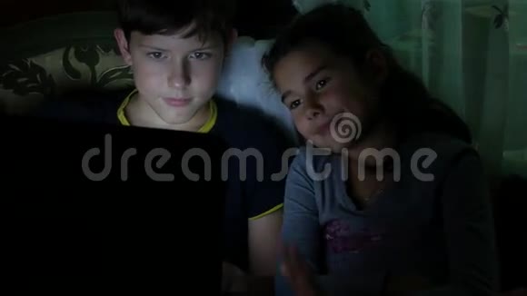 儿童男孩和女孩在笔记本电脑上玩夜间儿童在线游戏视频的预览图