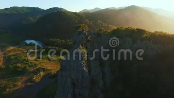 空中观景台在岩石上飞过一片美丽的阳光林树空中摄影机拍摄背景视频的预览图