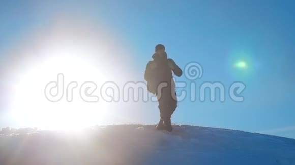 男子旅行者在冬季登山剪影阳光慢动作视频冬季旅行冒险生活视频的预览图