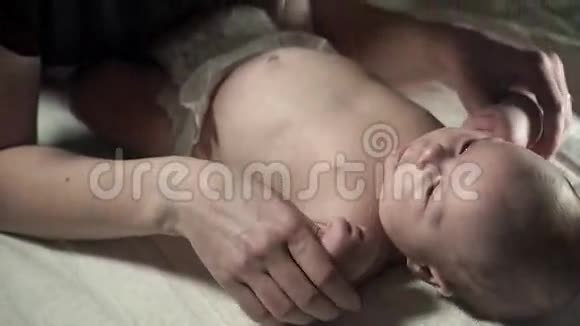 一个迷人的婴儿躺在床上一位年轻的母亲牵着他的手视频的预览图