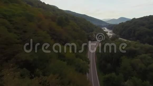 在一条乡村景观道路上飞行跟随一辆车行驶在上面上面有郁郁葱葱的绿叶农田空中射击视频的预览图