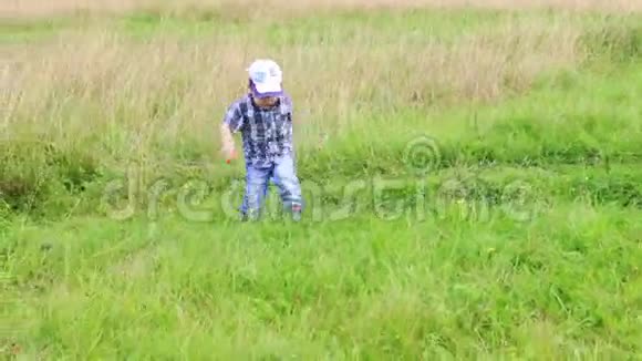 穿牛仔裤的小可爱男孩在草地上奔跑视频的预览图