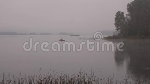 渔人划船坐在浓雾笼罩的湖面上的木船上4K视频的预览图