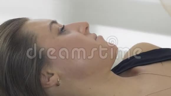 女孩的脸胸手躺在美容院的毯子下程序中的女孩视频的预览图