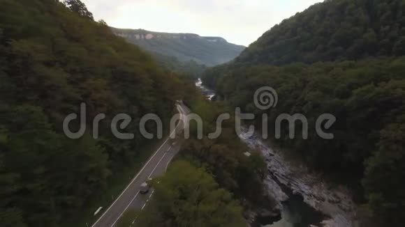 在一条乡村景观道路上飞行跟随一辆车行驶在上面上面有郁郁葱葱的绿叶农田空中射击视频的预览图