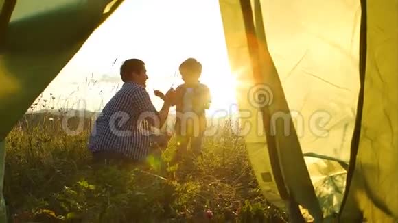 日落时分父亲和儿子在帐篷附近玩耍视频的预览图