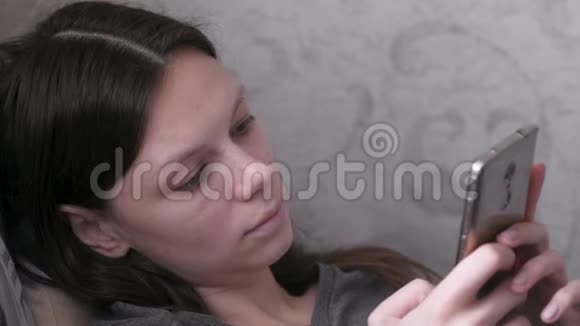 女人躺在沙发上用手机读东西视频的预览图