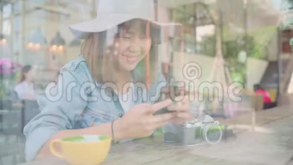 商务自由职业亚洲妇女使用智能手机交谈阅读和短信而坐在桌子上的咖啡馆视频的预览图
