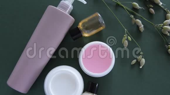在深绿色背景下的化妆品和野花的顶部视图健康美容治疗视频的预览图