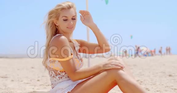 坐在沙滩上的金发美女视频的预览图