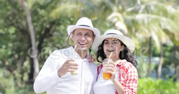 棕榈树下的夫妻谈饮汁热带度假的男女游客交流视频的预览图